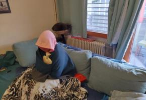 Une locataire munie d’une bouillotte et emmitouflée dans une couverture dans son séjour. TR