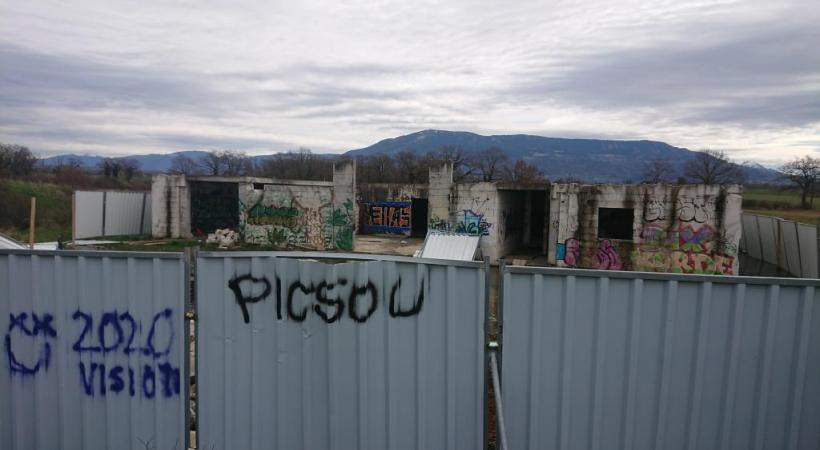 Le bâtiment couvert de tags est entouré de barrières en tôle. MP